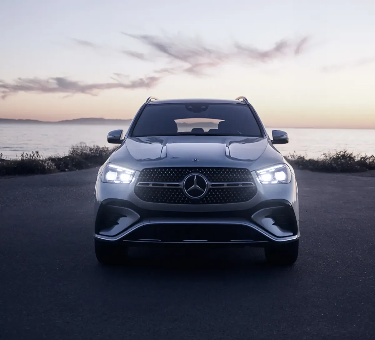 A 2026 Mercedes-Benz GLE SUV at a coastal sunset, headlights on, the kind of Emerald Coast setting these buyers drive, from Mercedes-Benz of Fort Walton Beach, Florida
