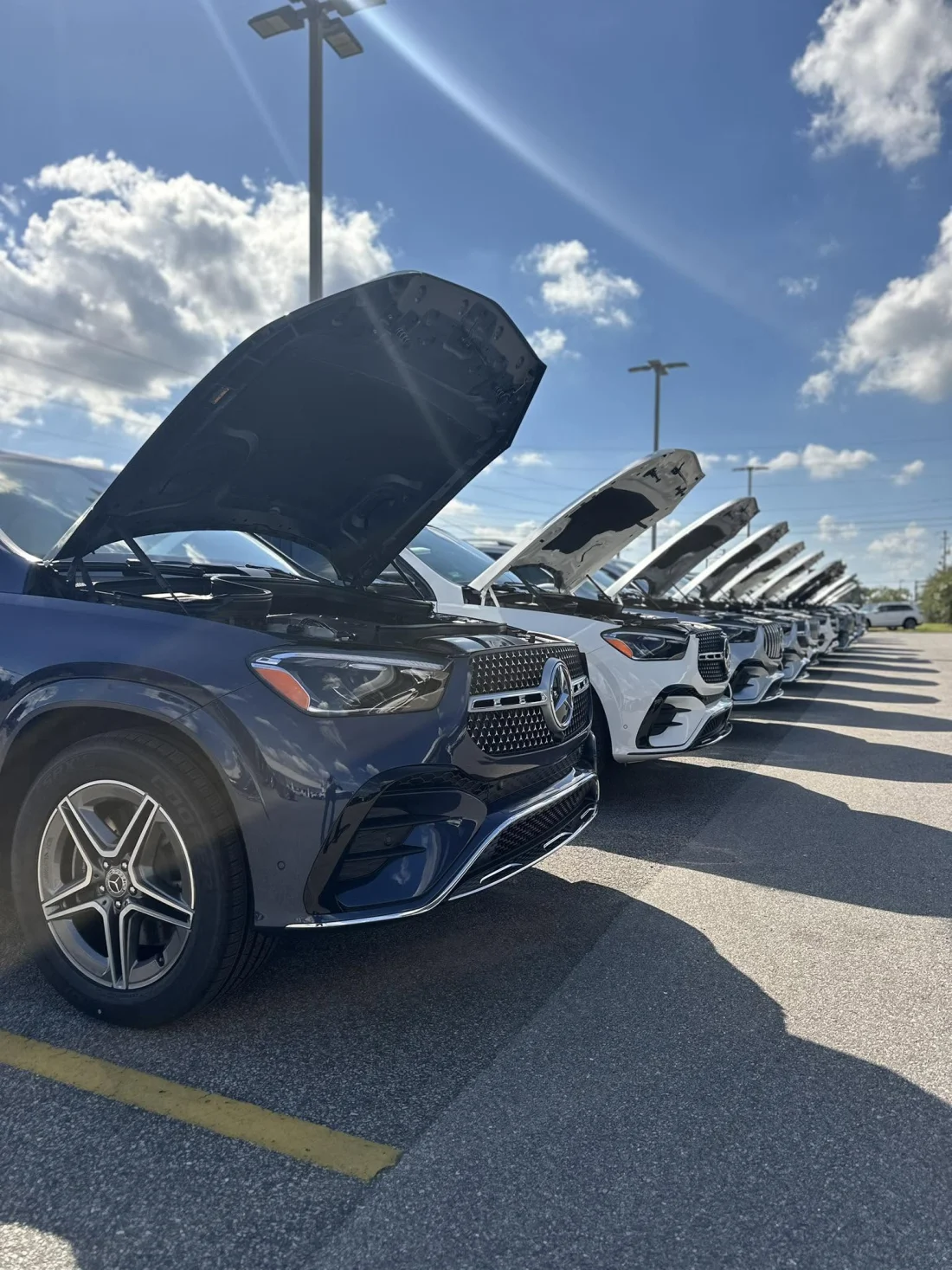 A row of Mercedes-Benz SUVs with hoods up on the Fort Walton Beach lot, being inspected and reconditioned before they're priced