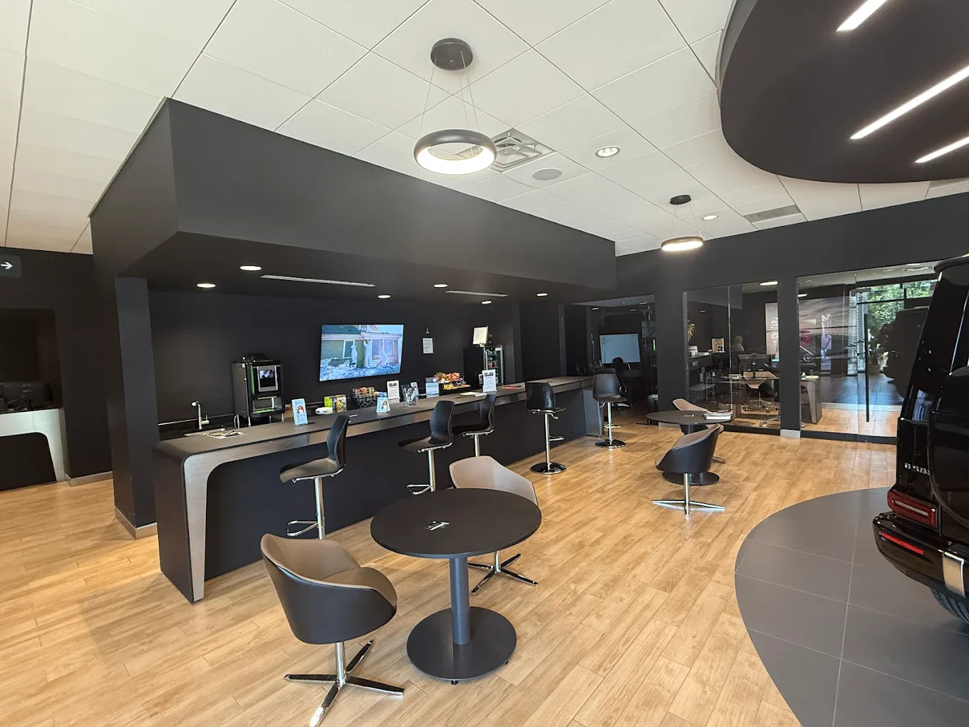 Inside Mercedes-Benz of Fort Walton Beach at 1000 Beal Parkway NW: the client lounge with a coffee and espresso bar, seating, and a vehicle on the showroom floor