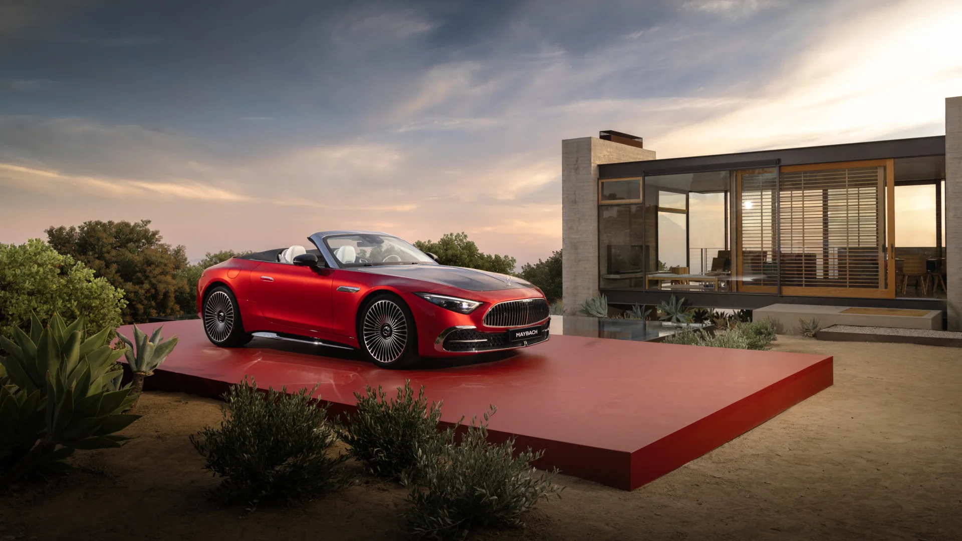 Red Mercedes-Maybach SL 680 roadster on a display plinth beside a modern glass villa at dusk, from Mercedes-Benz of Fort Walton Beach, 1000 Beal Parkway NW, Florida