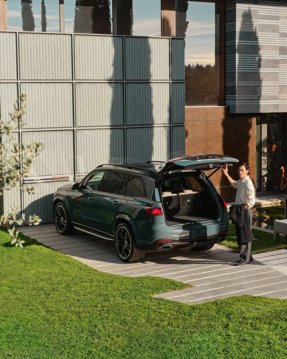 Mercedes-Benz GLS with the power tailgate open in a modern villa driveway, the arrival-home moment the three-row flagship is built around
