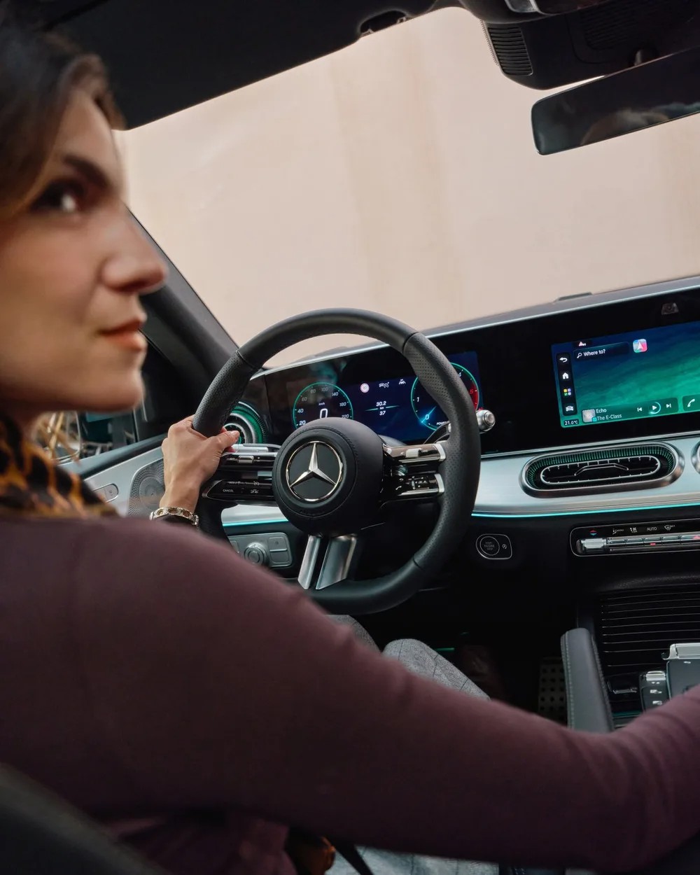 Driver at the wheel of a modern Mercedes-Benz cabin with widescreen displays, the flagship interior standard behind the 'S-Class of SUVs' line