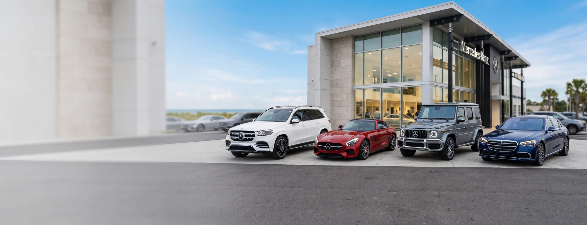 Mercedes-Benz of Fort Walton Beach dealership with a white GLS SUV, red AMG GT coupe, gray G-Class and blue S-Class sedan parked out front