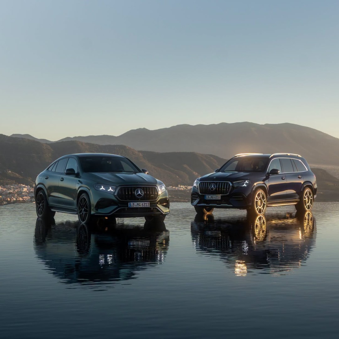 Mercedes-AMG performance SUVs parked beside a reflective waterfront with mountains in the background, showcasing luxury design and available at Mercedes-Benz of Fort Walton Beach.
