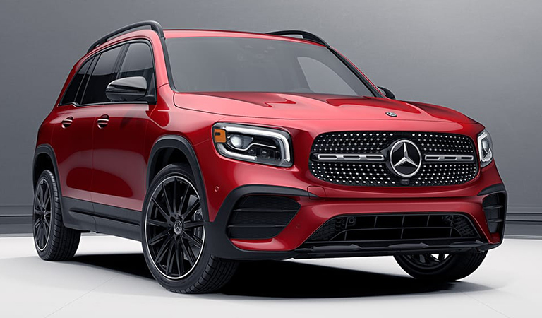Red Mercedes-Benz GLB compact luxury SUV in a front three-quarter studio view against a grey backdrop, showing its upright boxy roofline and black alloy wheels