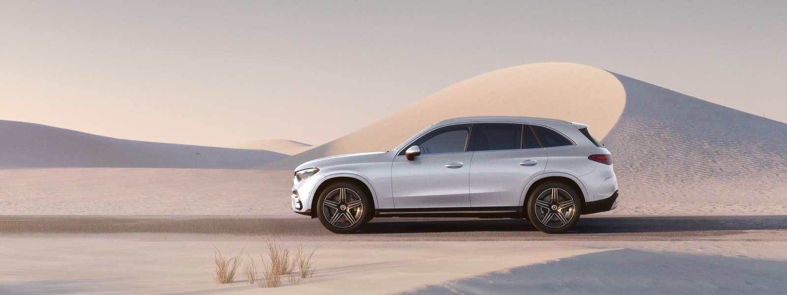 A Mercedes-Benz GLC SUV among sand dunes in warm evening light.