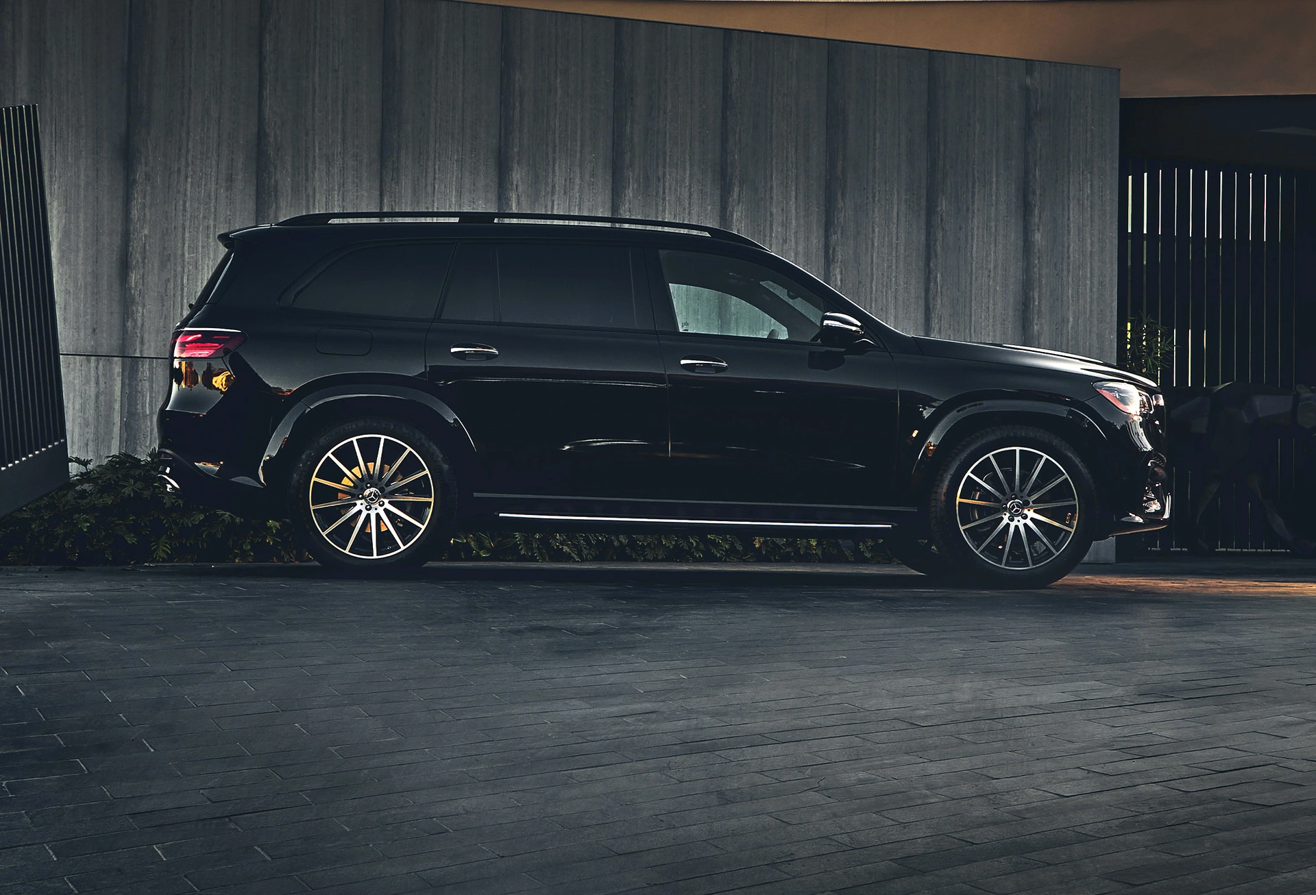 A Mercedes-Benz GLS SUV parked at a modern house in evening light, side view