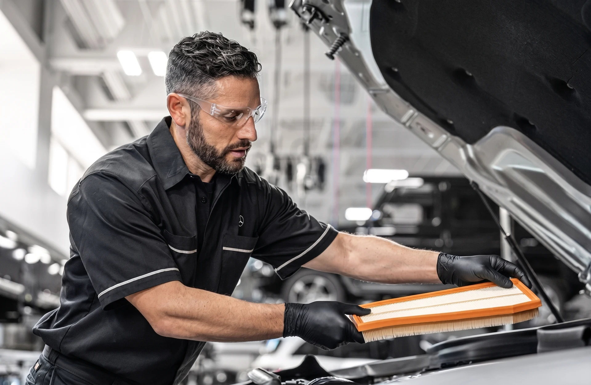 A Mercedes-Benz technician fitting a new engine air filter at the open hood